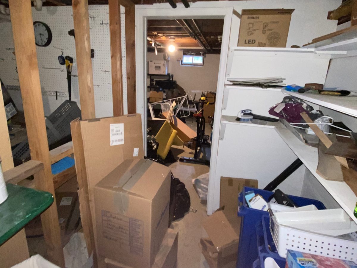Basement storage area packed with boxes, shelves, and household items before a cleanout