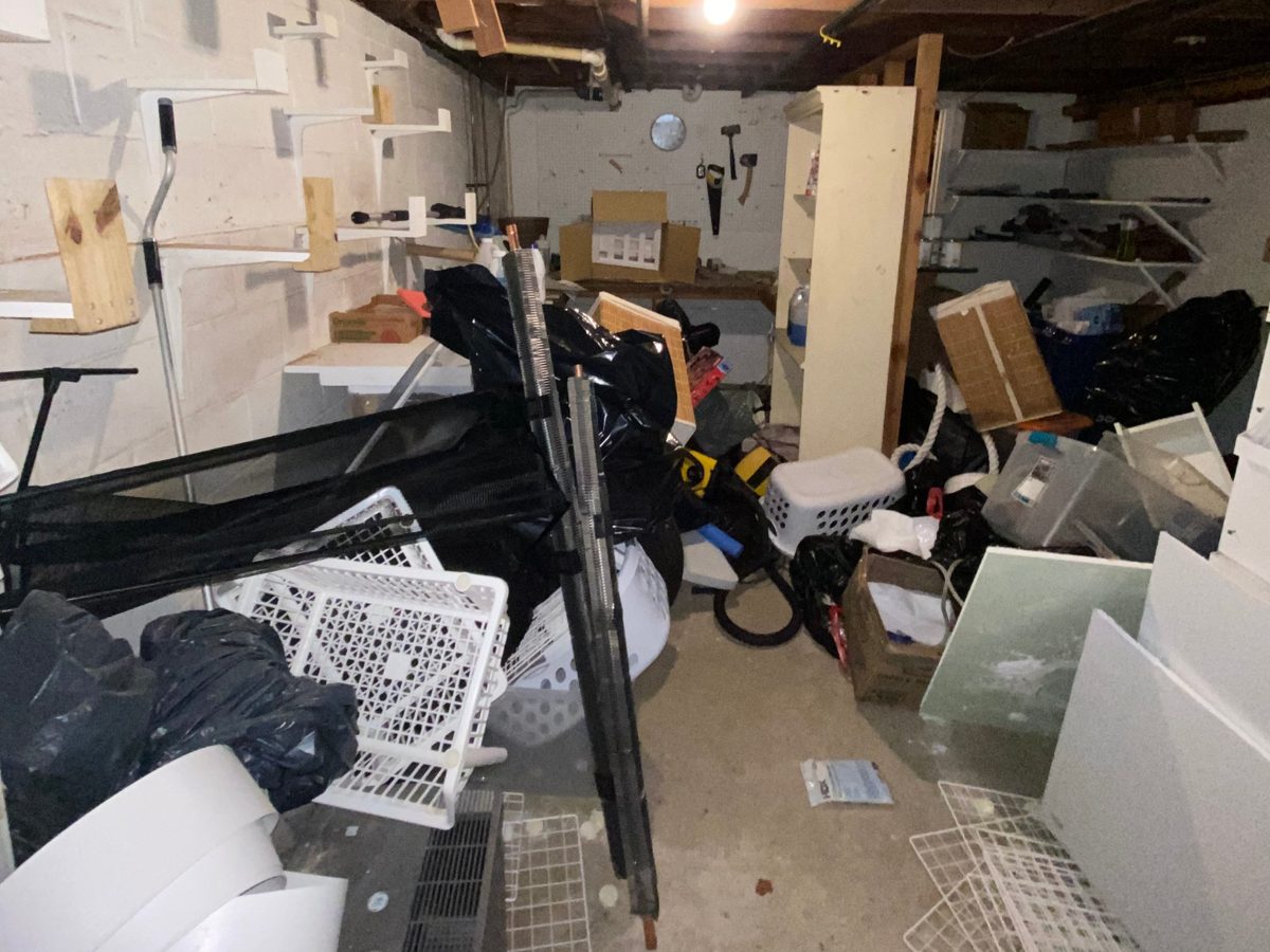 Basement workshop area crowded with bags, bins, and materials before a cleanout