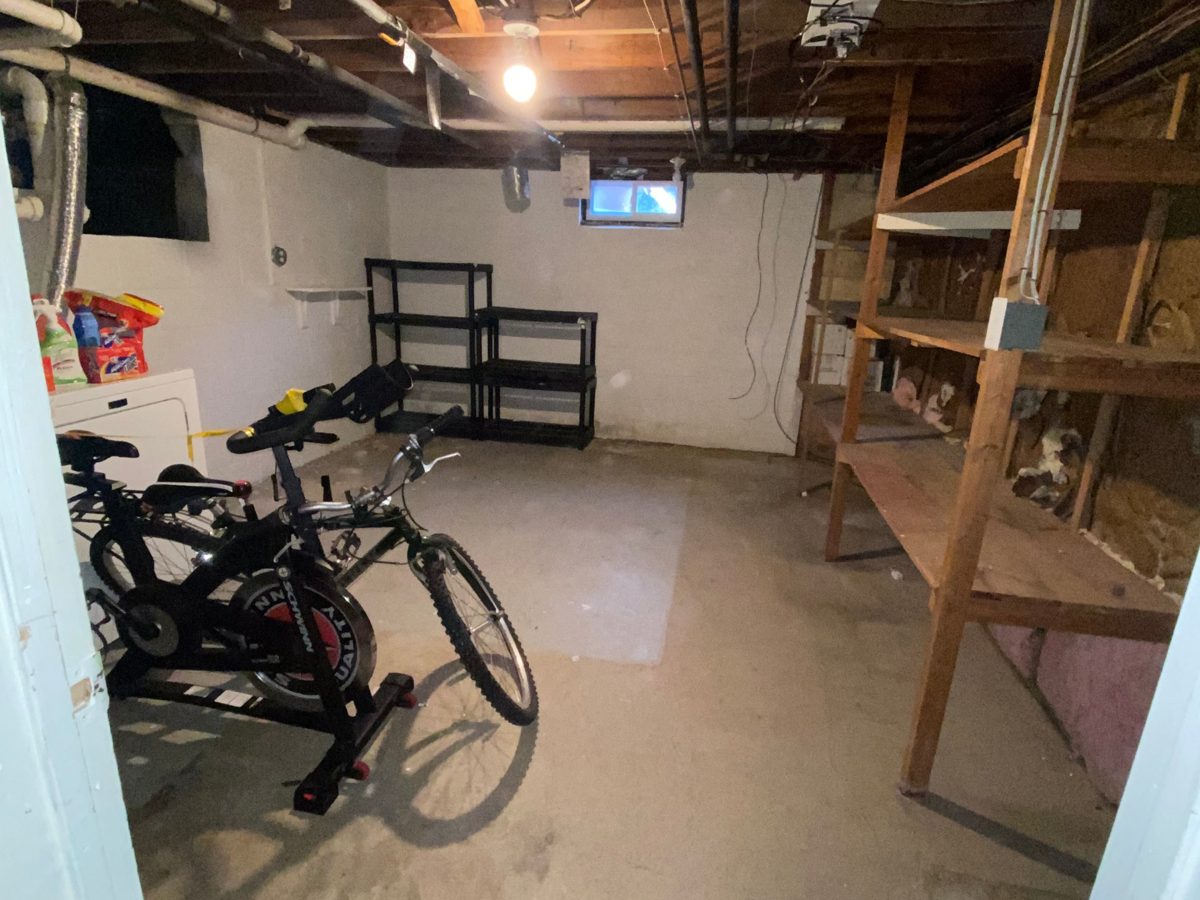 Basement laundry area cleared out, with only a bike and shelving left