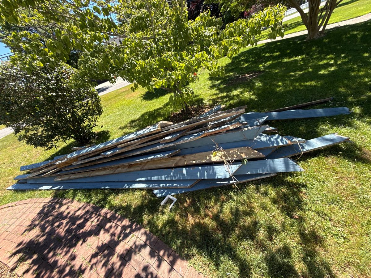 Pile of long blue-painted deck boards on a lawn