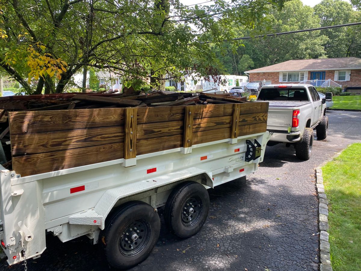 Dump trailer loaded with old wood and lumber debris in a driveway