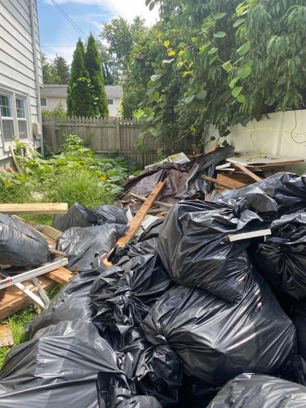 Black trash bags and lumber piled in a side yard