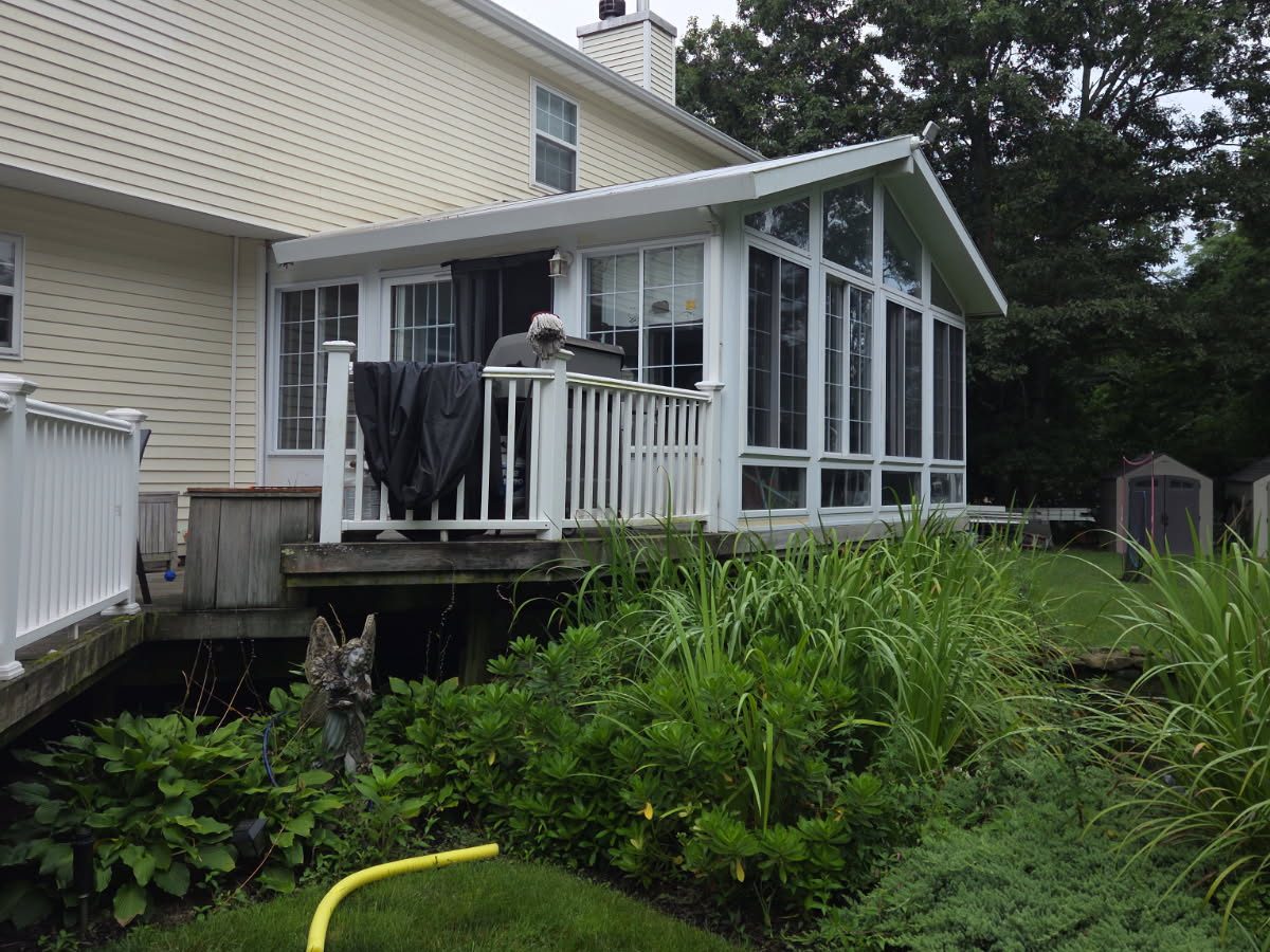 Sunroom attached to the back of a house, with a deck, before removal