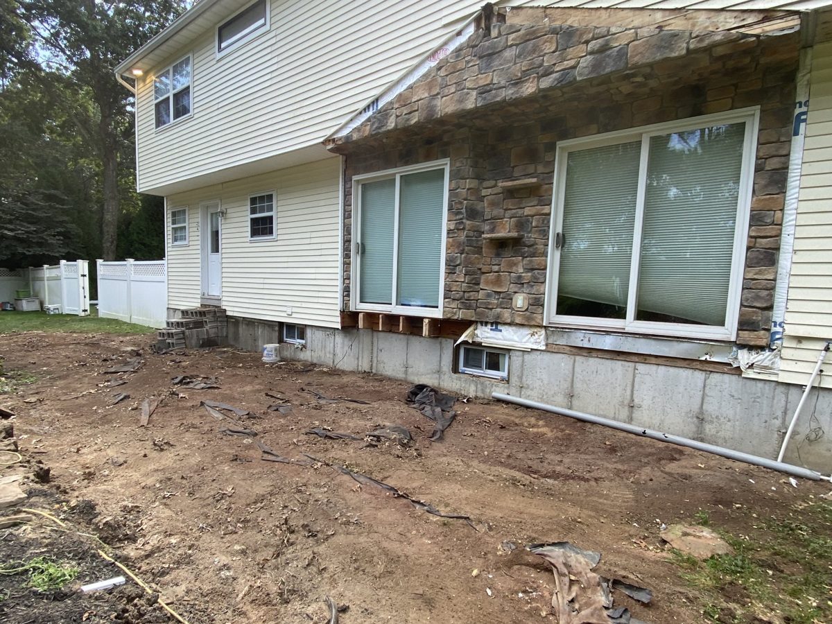 Back of the house with the deck and sunroom removed and the yard cleared down to dirt