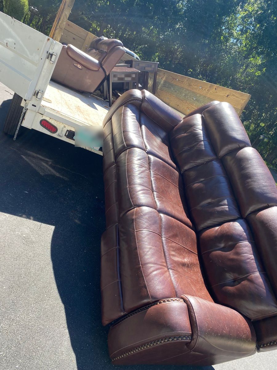 Leather couch and recliner being loaded onto a dump trailer