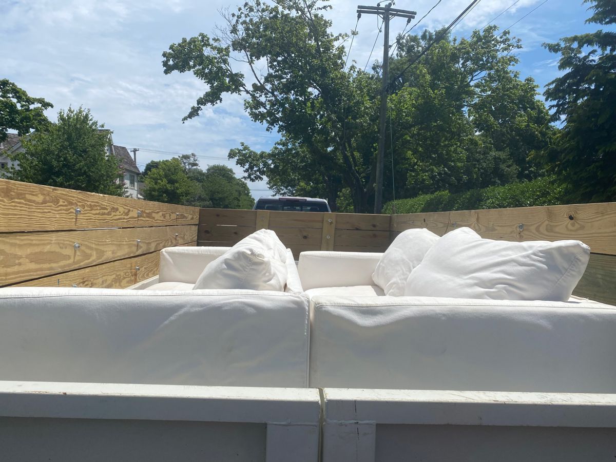 Two white sofas loaded into a dump trailer