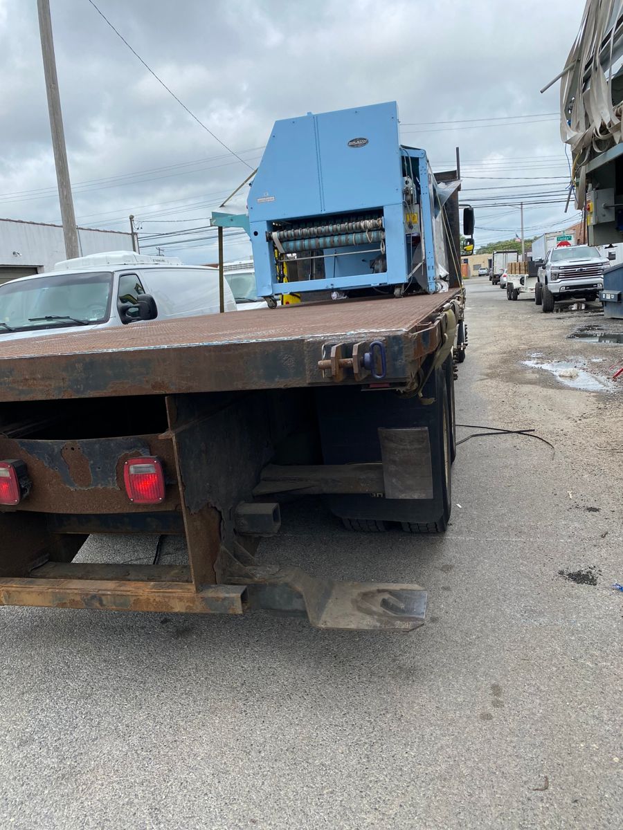Industrial machine strapped onto a flatbed truck on the street