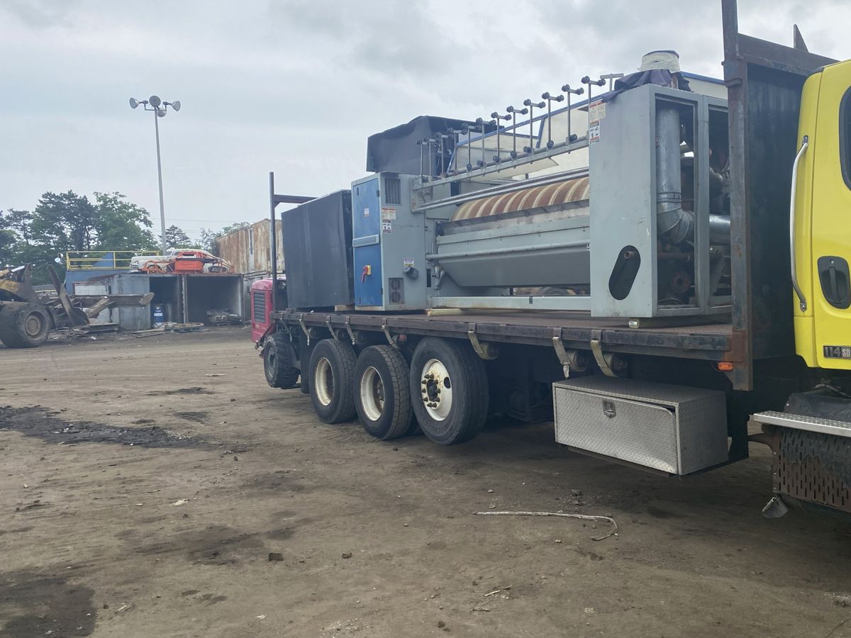 Flatbed truck carrying the industrial machine to a recycling yard