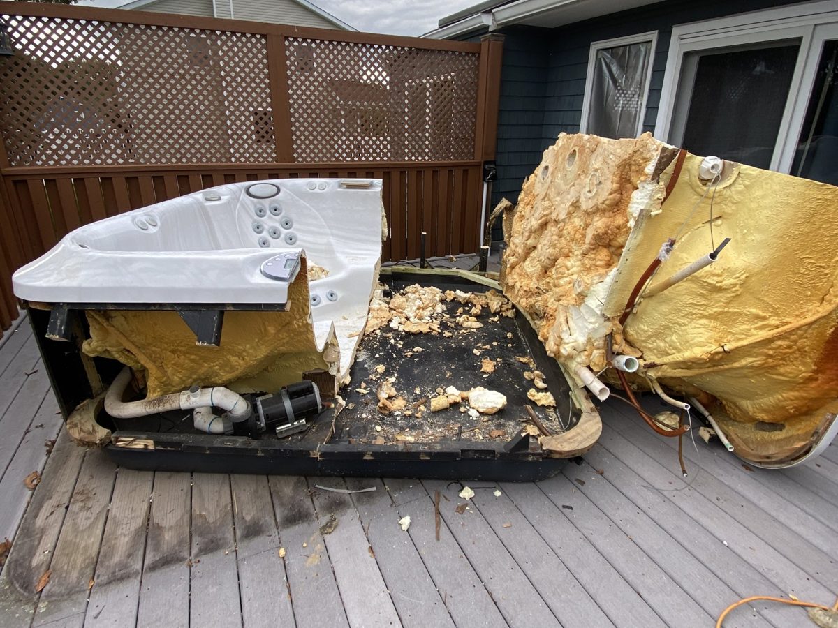 Hot tub broken apart on a backyard deck during removal