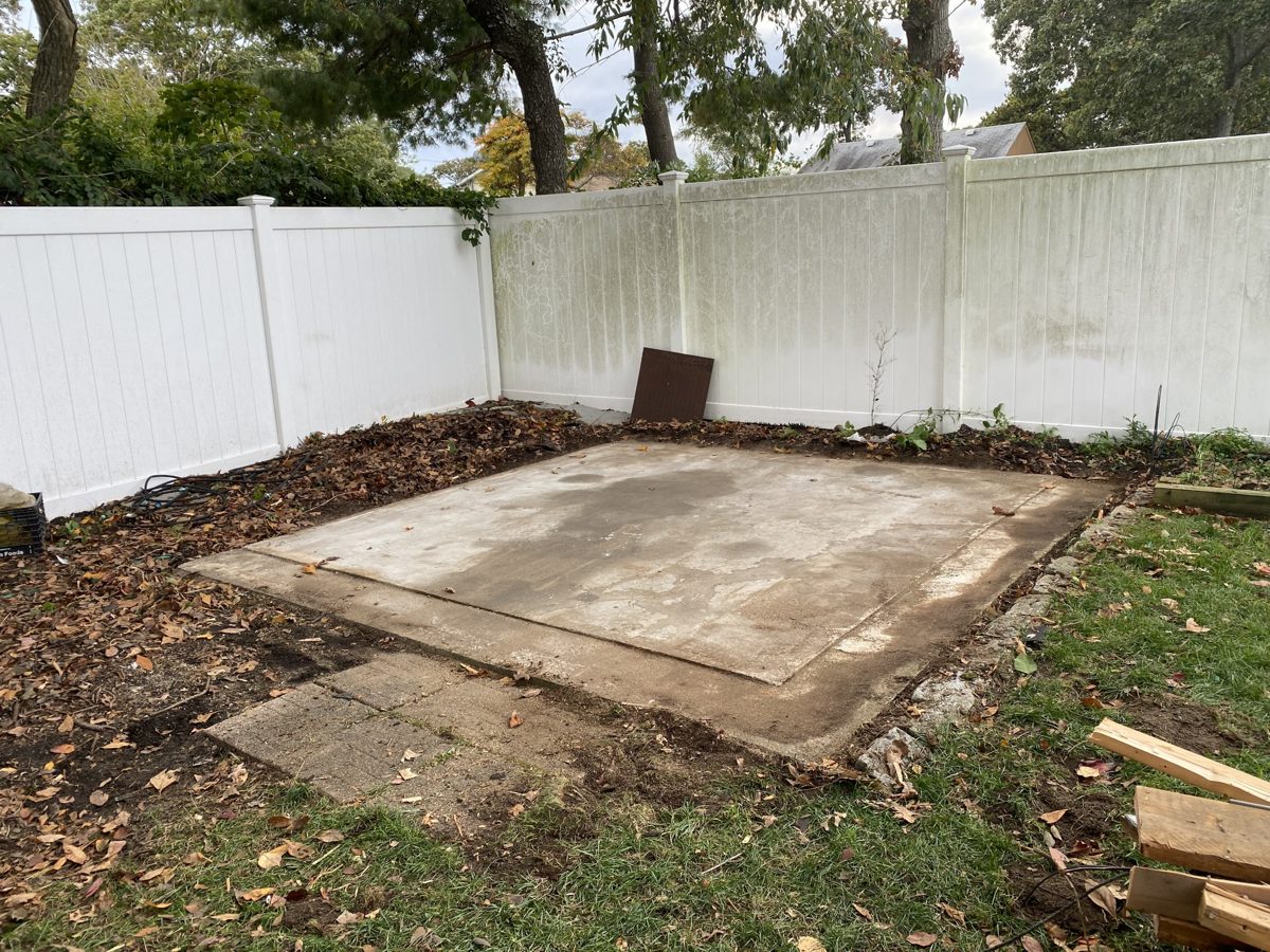 Empty concrete pad in a fenced backyard after the shed was removed