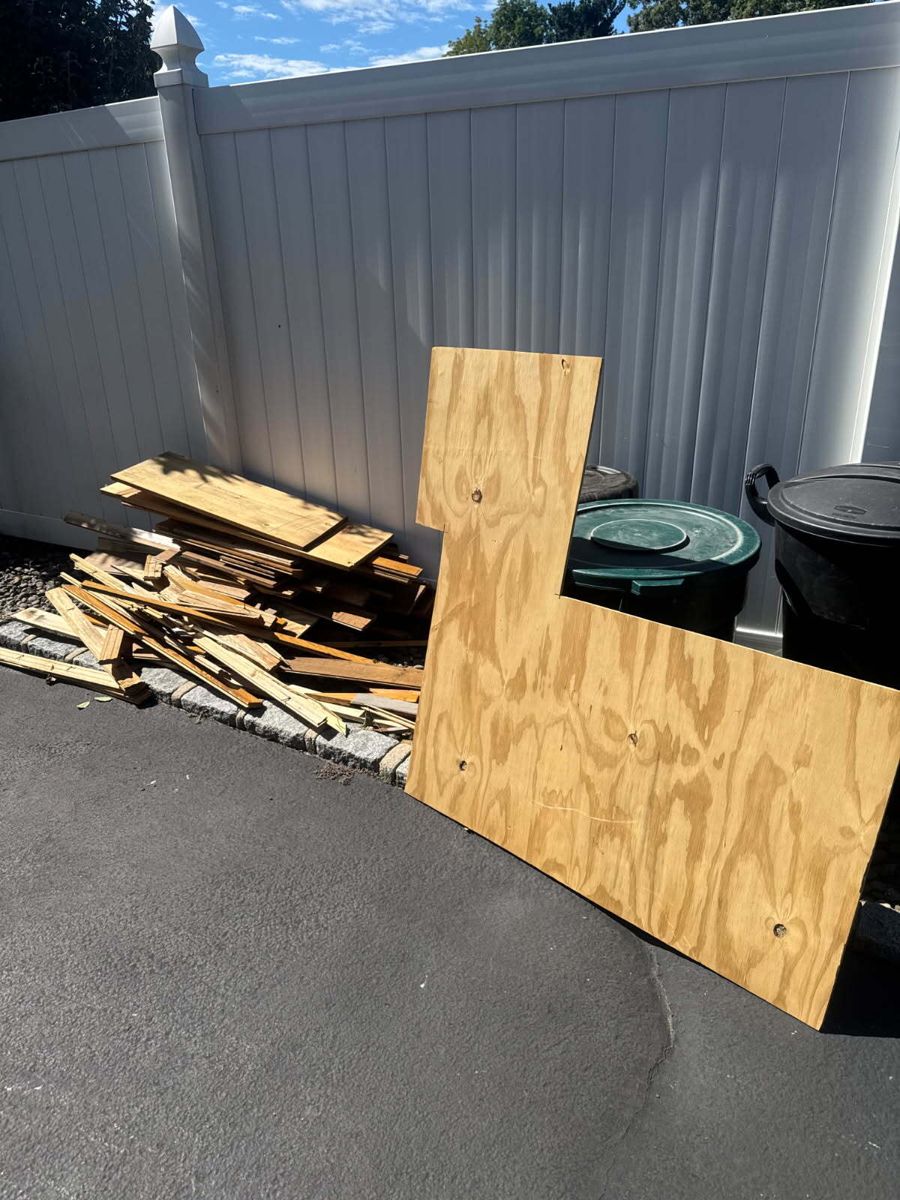 Plywood sheet and a pile of scrap lumber beside a driveway