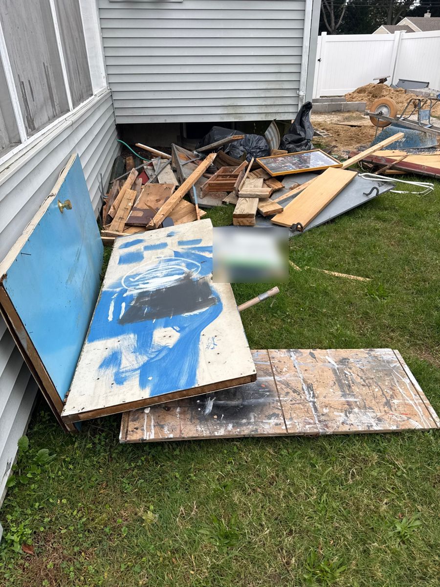 Old doors, boards, and lumber piled along the side of a house
