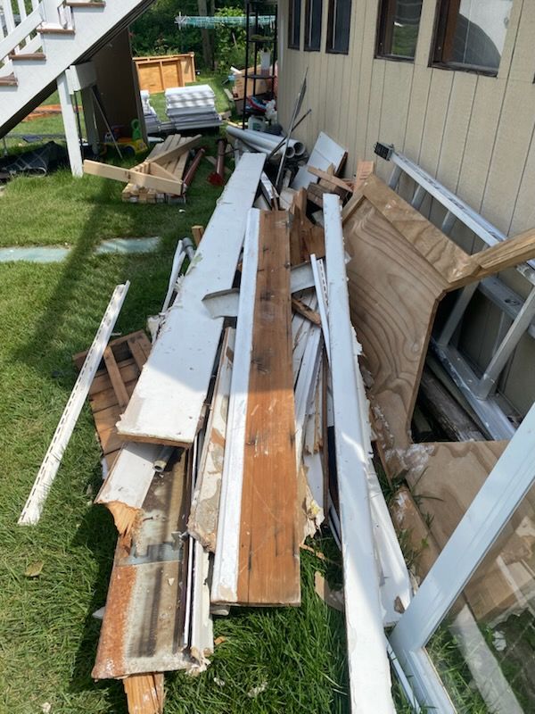 Pile of old siding, boards, and trim beside a house
